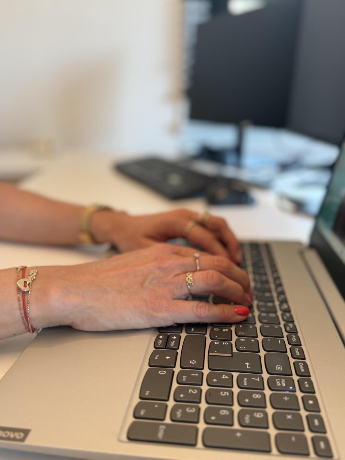 Gros plan des mains de Stéphanie tapant sur le clavier d’un ordinateur portable